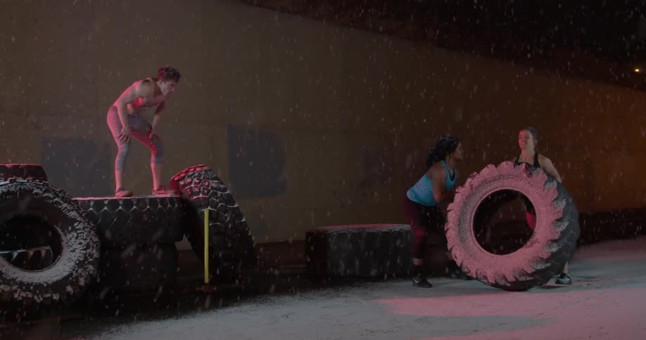 People are lifting tires at night as it snows
