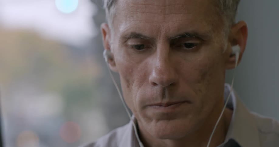 Closeup of a man looking at something while wearing earbuds