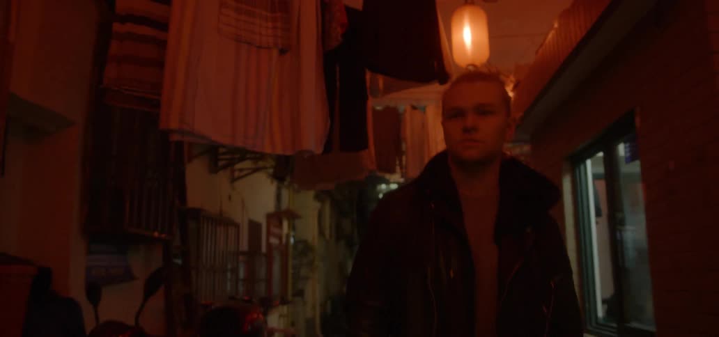 A young man is walking down a city alleyway at night