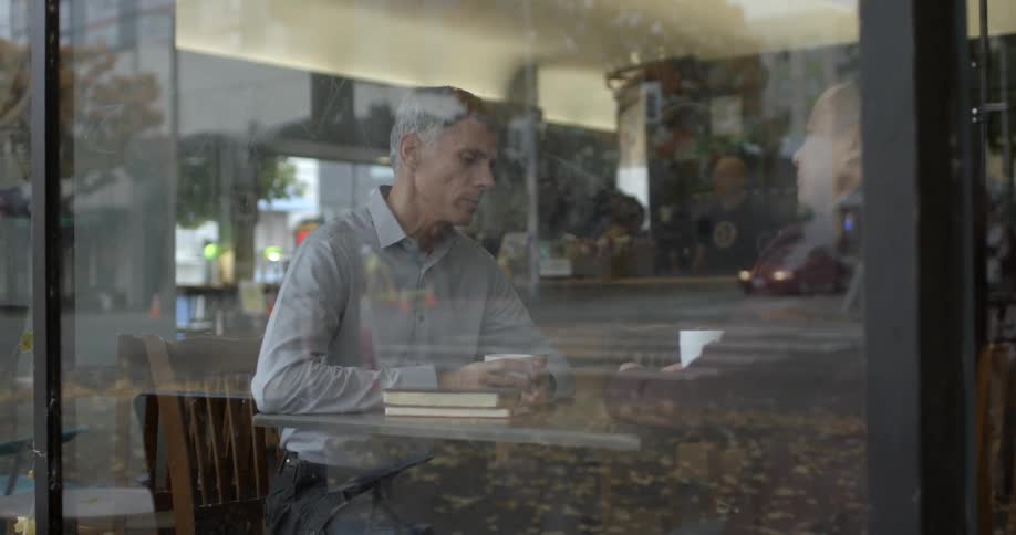 Two men have a discussion while sitting in an urban coffee shop