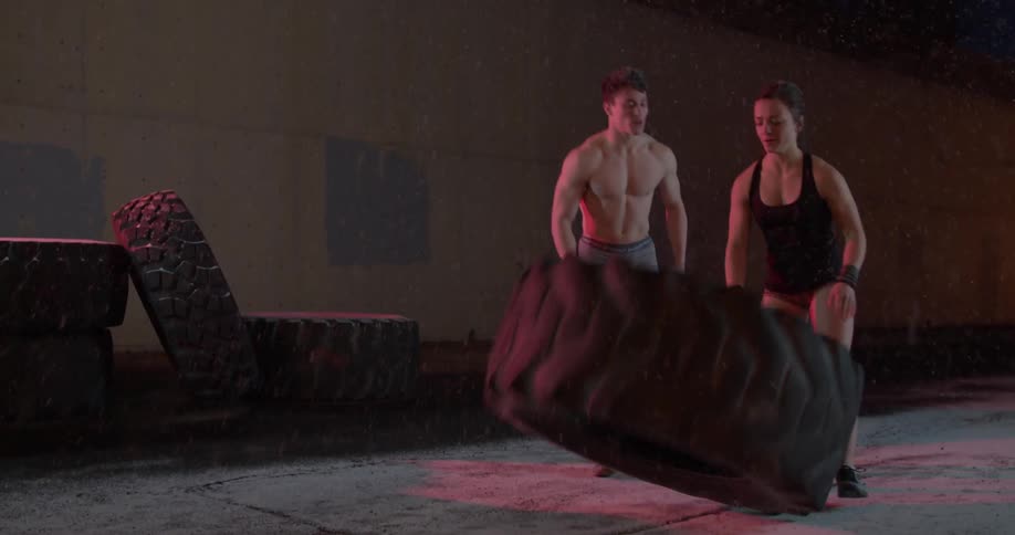 A woman pushes a tire over at night