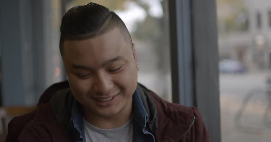 An asian man laughs as he sits in conversation