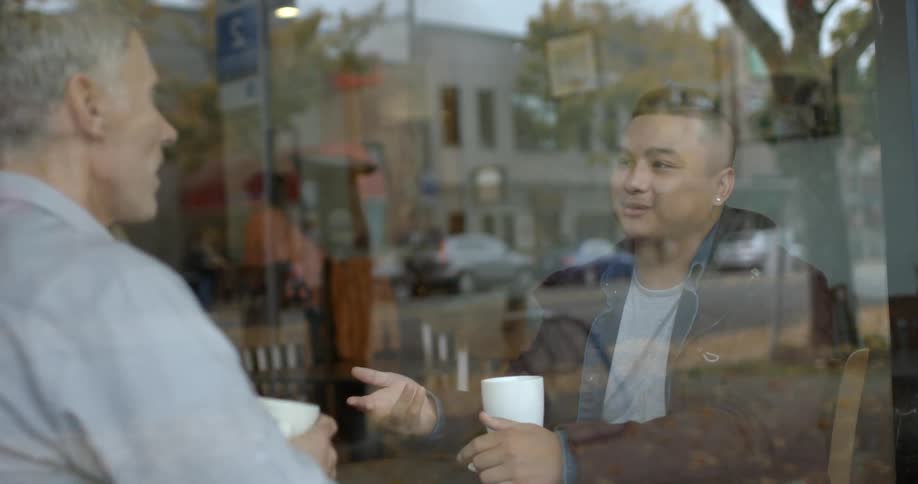 Two men chat over coffee in a coffee shop
