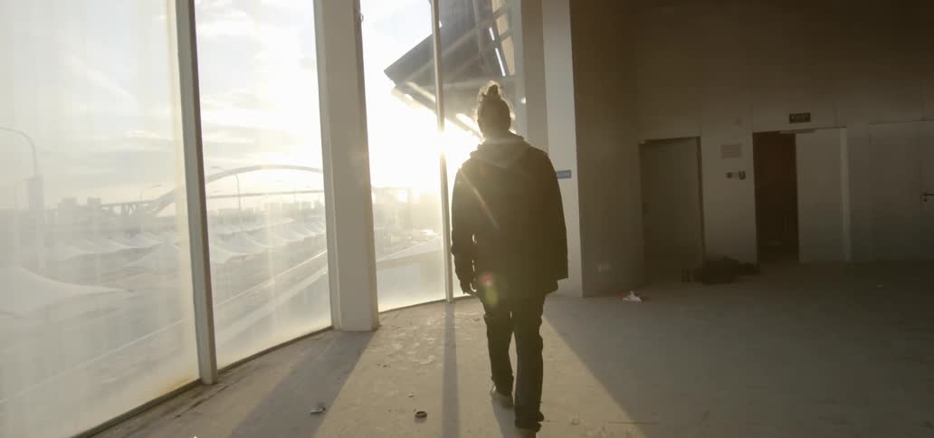 A man walks towards windows as sunlight streams in
