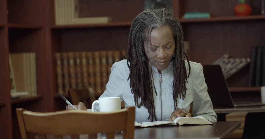 A woman is working in a library writing