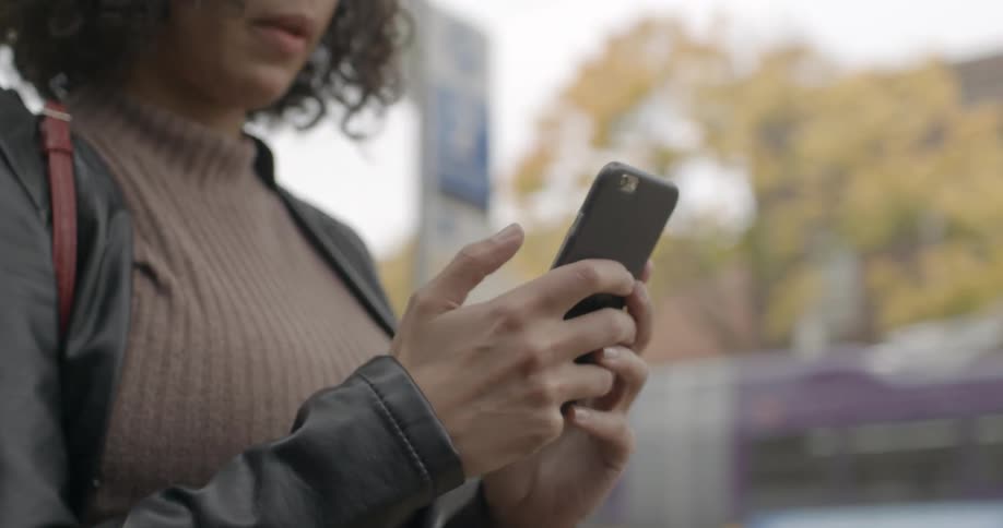 Woman looks at a phone in the middle of a city on a sunny day