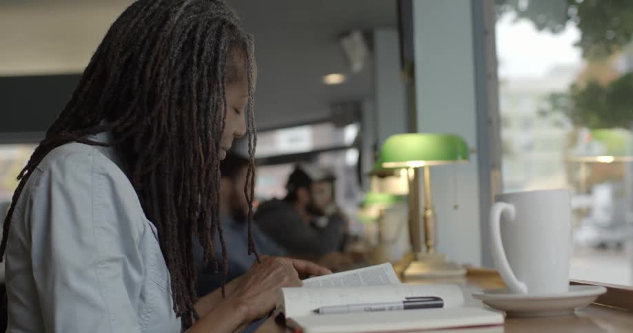 A woman is reading  book in a cafe