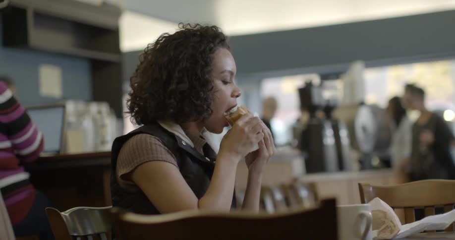 Woman eats a sandwich by herself in a cafe