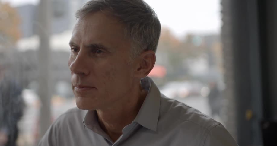 A man is talking as people walk outside