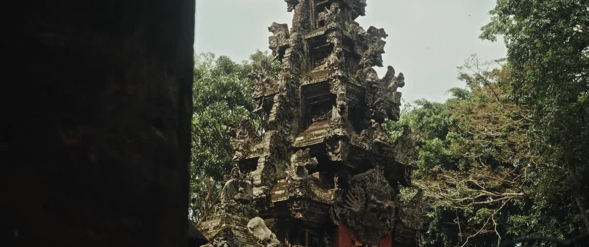 A slow tilt down shot reveals an ancient and ornate Balinese temple nestled in a lush green jungle