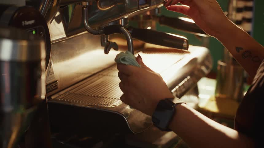 A barista purges and cleans the steam wand on a professional espresso machine in slow motion