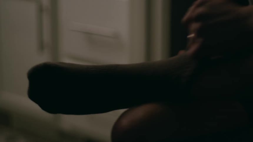 A  man puts a sock on his foot