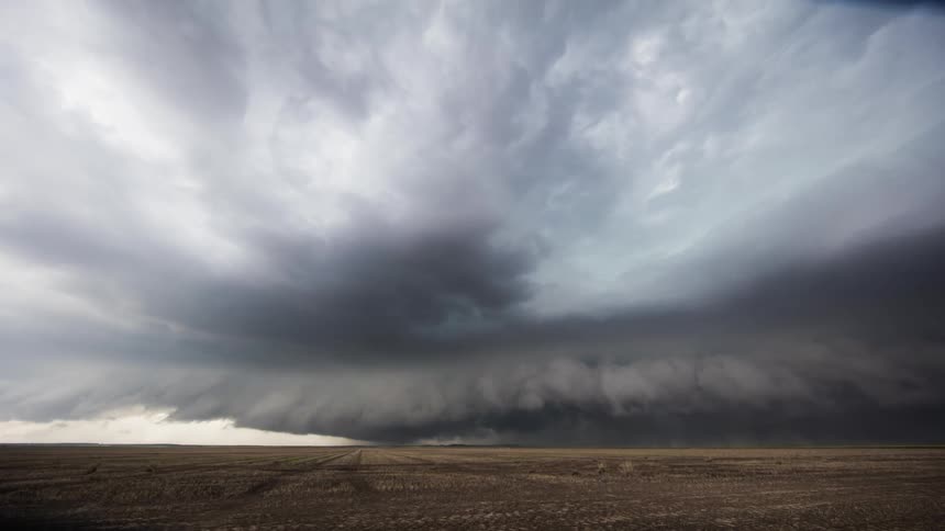 Storm clouds rotate and pass over an open field