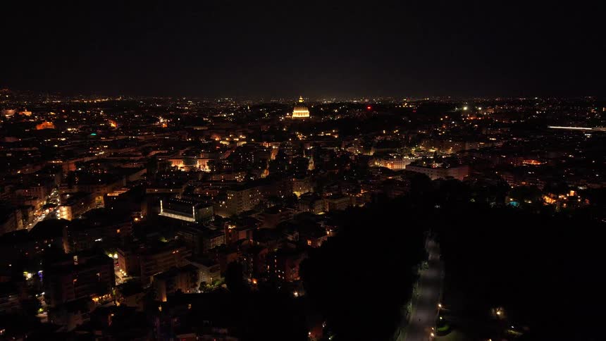 A breathtaking aerial pullback reveals the magnificent, illuminated cityscape of Rome at night, with the iconic St. Peter's Basilica dome glowing on the horizon