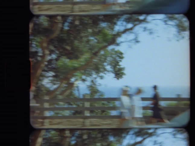 A vintage 8mm point-of-view shot driving along a scenic coastal road with the ocean in the background