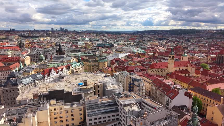 A stunning aerial flyover of the historic city of Prague, showcasing its iconic red rooftops and ancient architecture under a cloudy sky