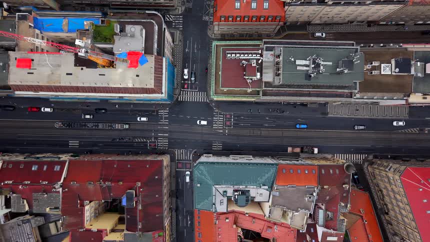 A slow top-down aerial zoom-out reveals a busy European city intersection with trams, cars, and pedestrians