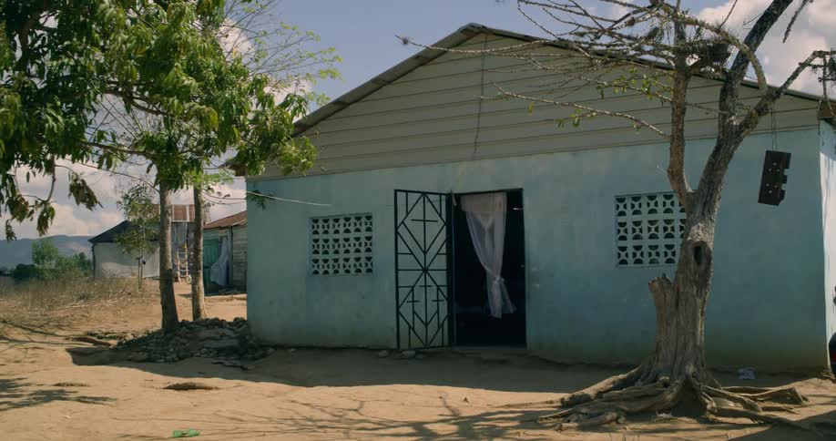 A slow push-in shot of a humble light blue house in a poor, rural village