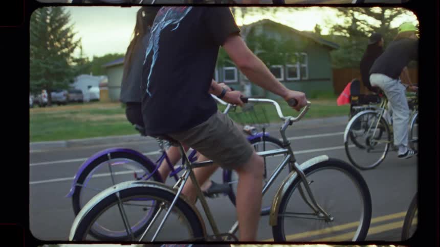 A group of friends on a leisurely bike ride through a suburban street during a sunny golden hour