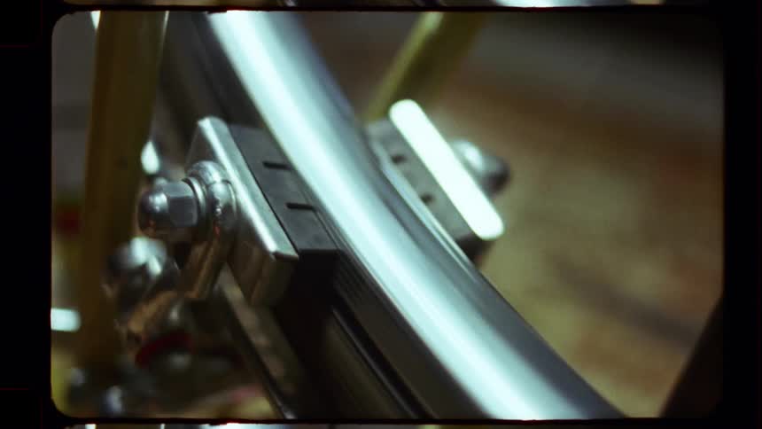 A close-up shot of a vintage bicycle wheel spinning and engaging the brakes, captured on film
