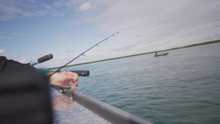 A first-person perspective of fishing from a boat on a calm river, with another fishing boat visible in the distance