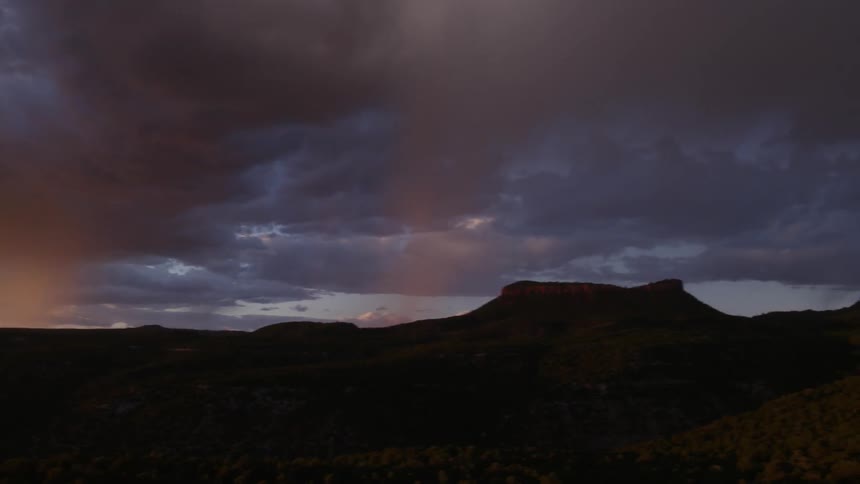 Storm clouds hover over a desert landscape