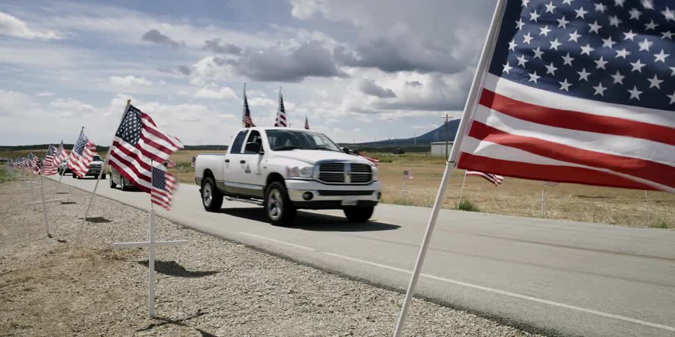 Cars drive past flags blowing in the wind