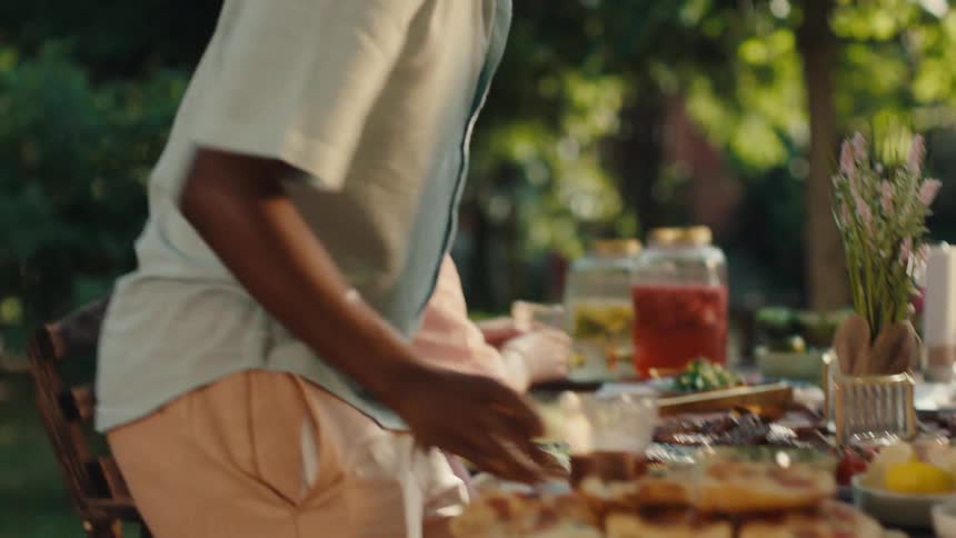 Friends enjoy a sun-drenched garden party, serving themselves fresh salad and bread from a communal table