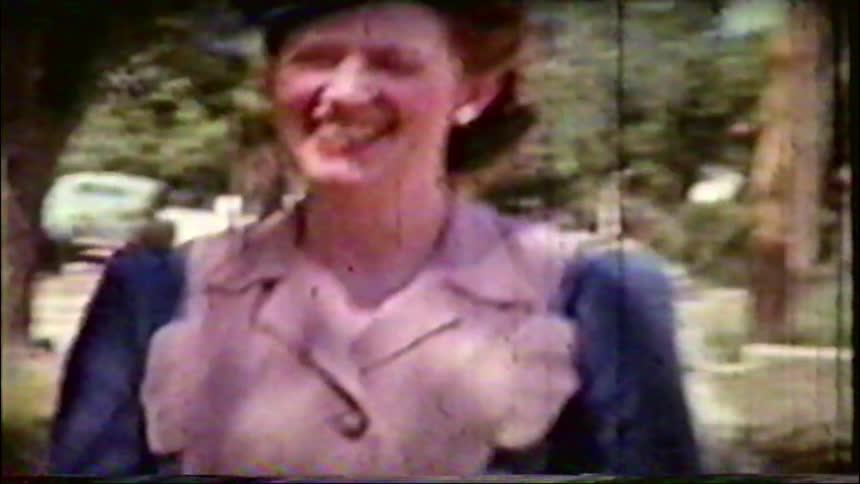 A happy woman in a stylish hat smiles and laughs in a park in this vintage 1940s home movie
