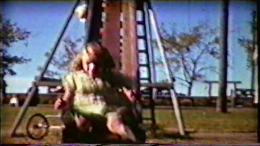Charming vintage 8mm footage captures two young girls laughing as they go down a very tall playground slide