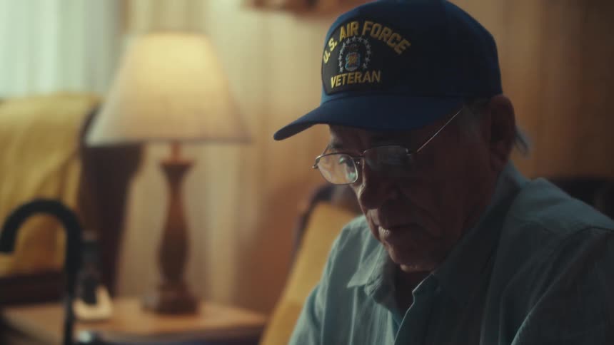 An elderly Air Force veteran meticulously sorts through a pile of receipts while calculating his finances at home