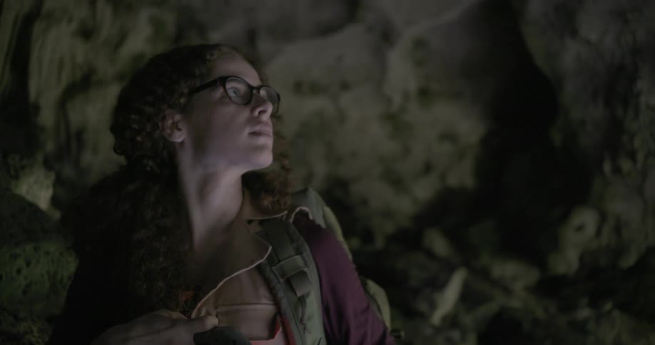 A woman is searching a cave