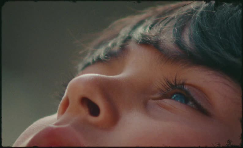 Dreamy vintage-style extreme close-up of a child's innocent blue eyes looking up in wonder before gently closing to sleep