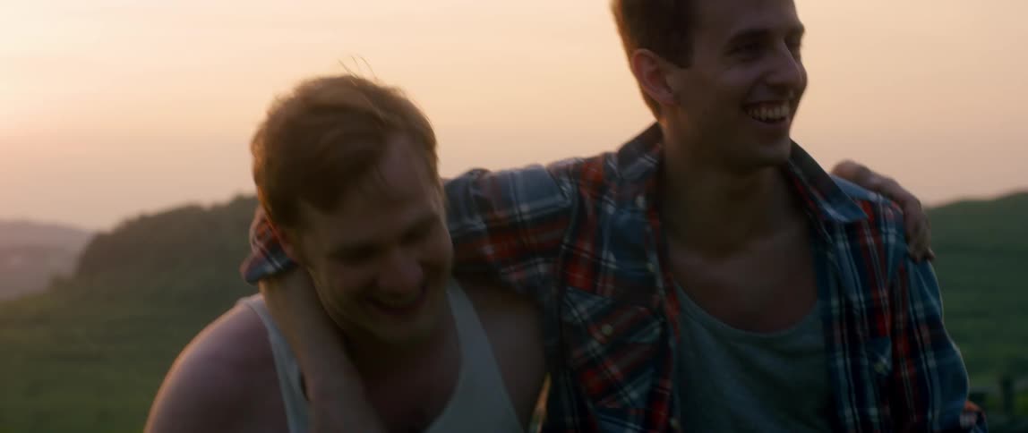 Two men walk and laugh with their arms around each others back