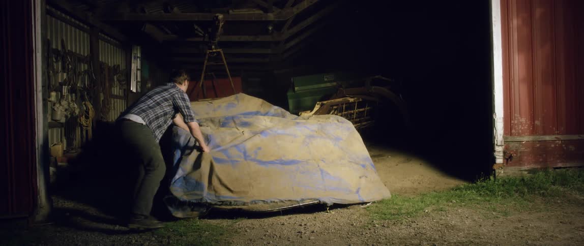 A man walks over and removes a cover from a car