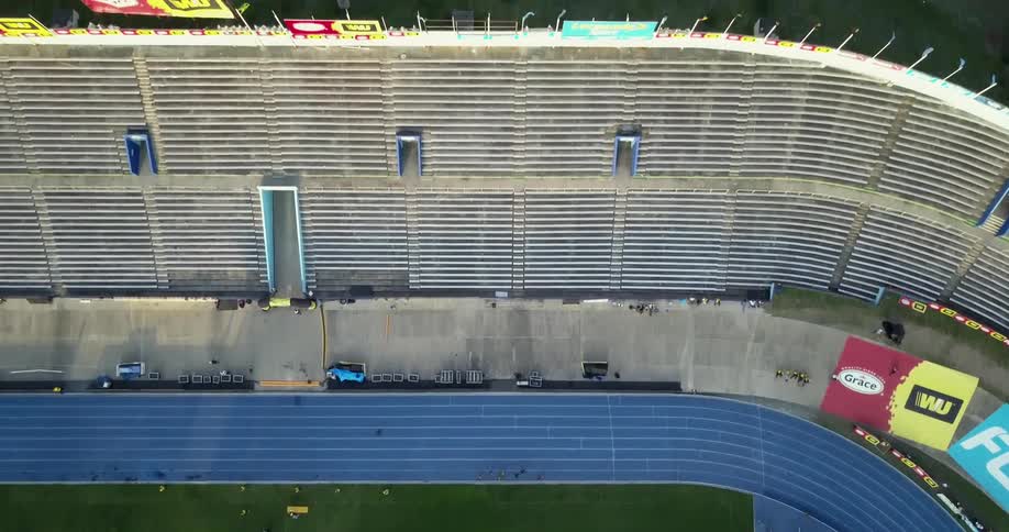 Runners run along a track in a stadium