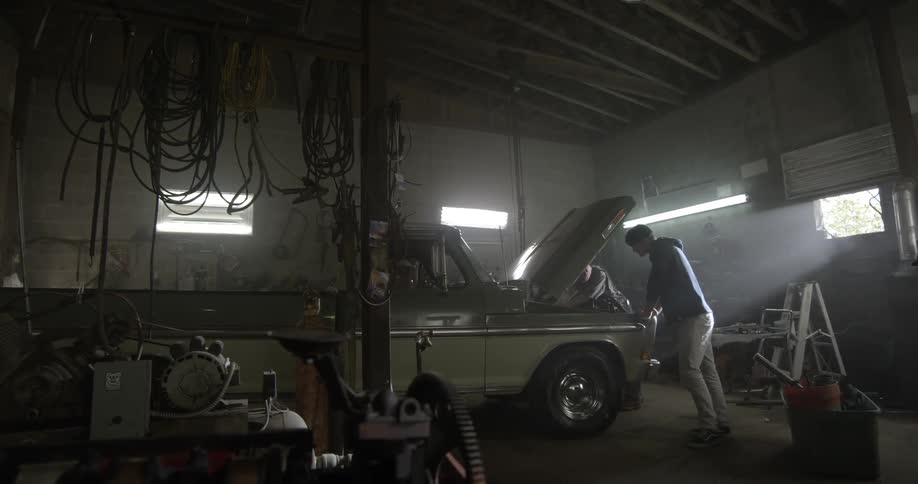 Two men work on a car in a garage