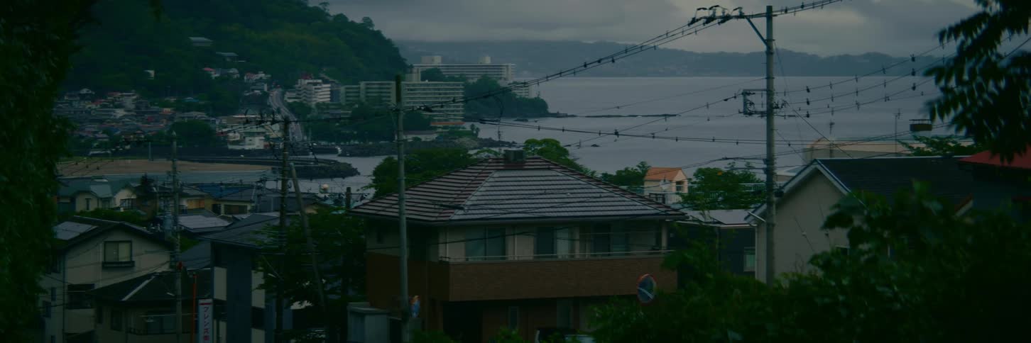 A static shot of a quiet Japanese coastal town overlooking the ocean on a gloomy, overcast day