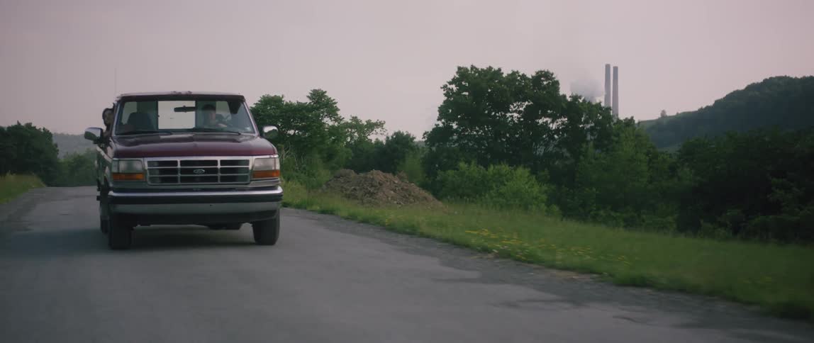 A pickup truck is driving down a rural road