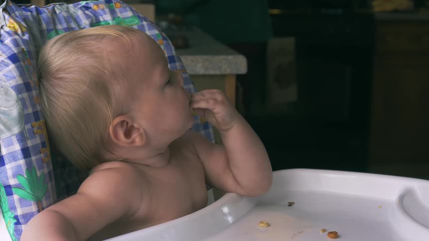 A baby eats in a high chair
