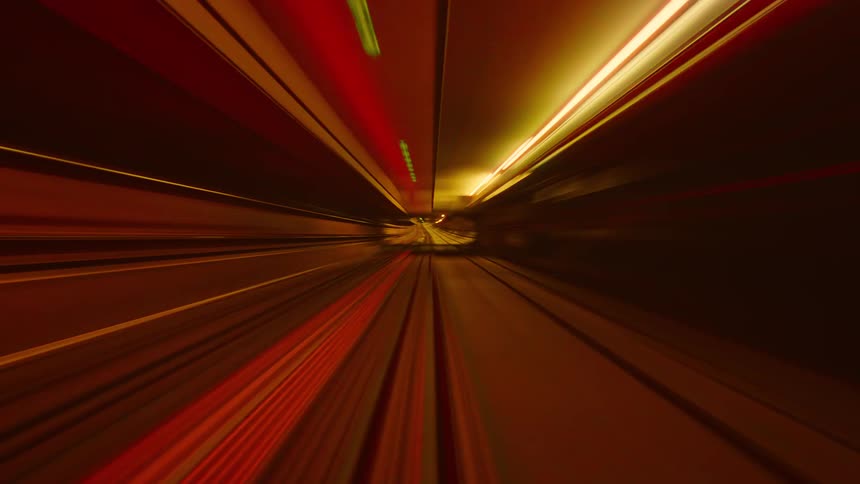 Abstract point-of-view time-lapse of a speeding subway train creating colorful light trails in a dark tunnel