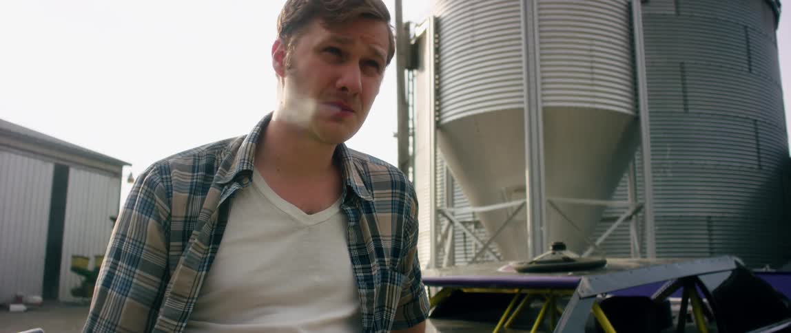 A man in a plaid shirt smokes outside