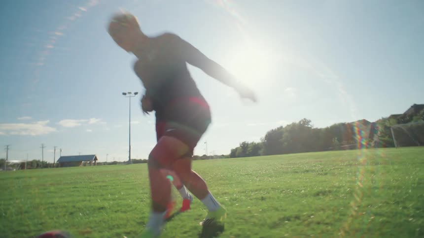 Dynamic slow-motion footage of two soccer players practicing their dribbling skills on a sunny field