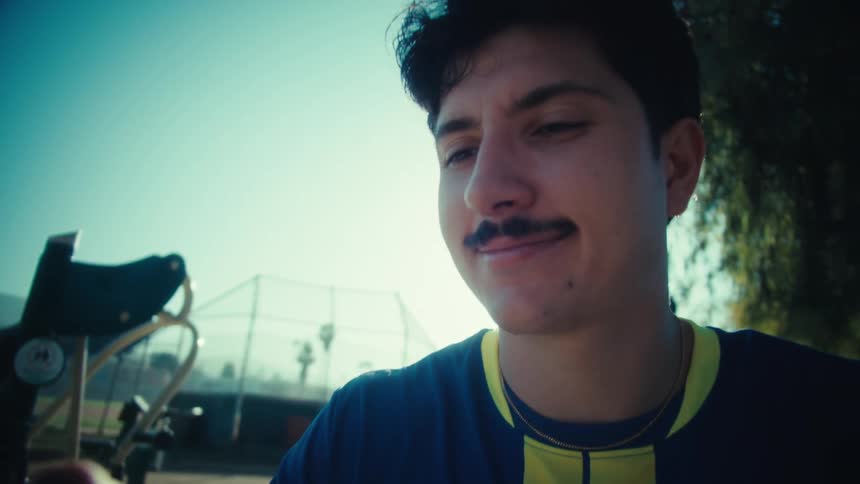 Low angle shot of a young soccer player smiling and taking a selfie at a sunny park