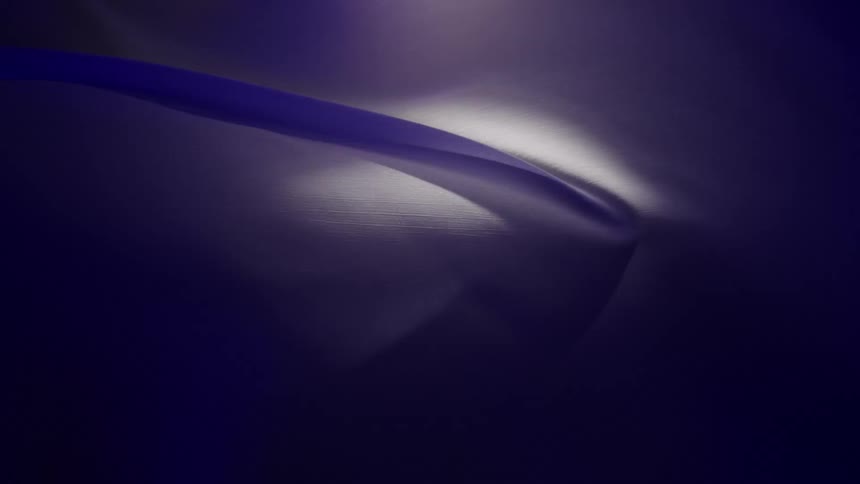 A dark blue, silky, abstract background moves and ripples in slow, elegant waves