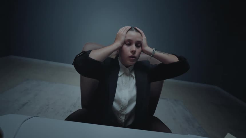 An exhausted businesswoman experiences burnout and stress while sitting at her desk late at night in a dark office