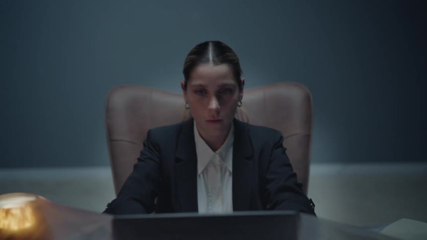 Surreal slow pull-back shot reveals a serious businesswoman working at her desk which is completely covered in a protective plastic sheet