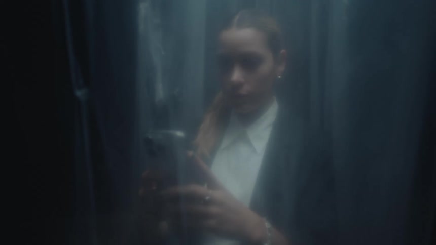 Misty shot of a businesswoman in a suit scrolling on her smartphone while standing behind a foggy barrier