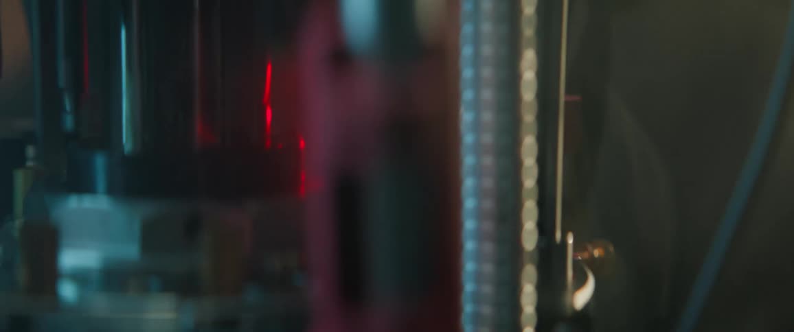 A red laser beam moves through a complex optical setup in a dark scientific laboratory