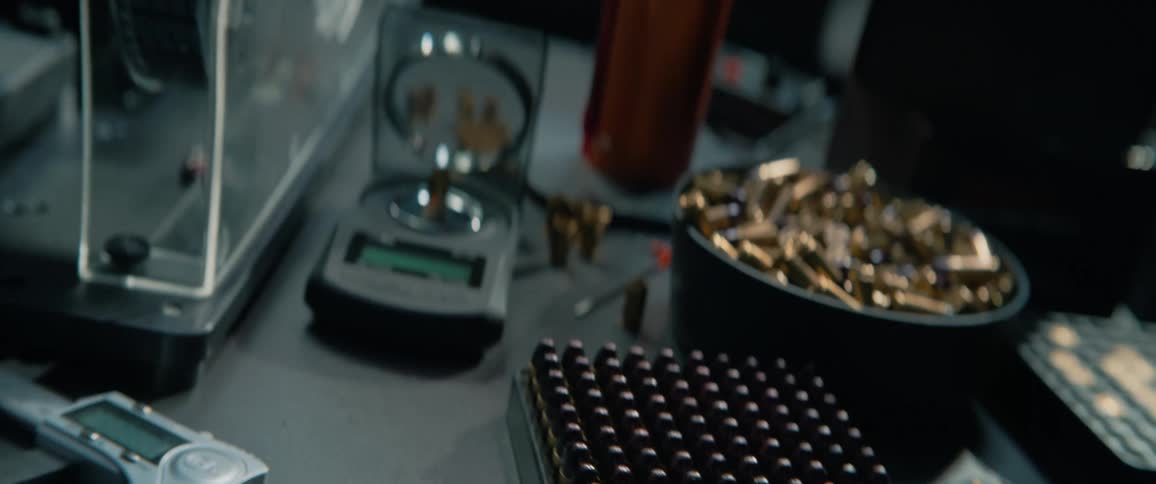 Close-up cinematic shot revealing trays of bullets and reloading equipment on a workbench